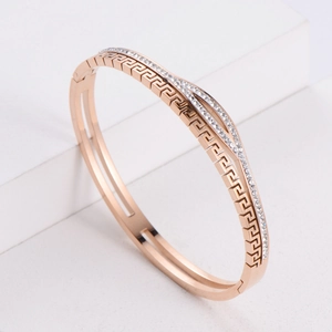 Rose gold bangle with geometric hollow pattern and micro-set cubic zirconia on pedestal