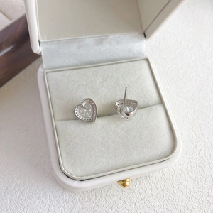 Macro shot of silver heart studs with white cubic zirconia in a jewelry box