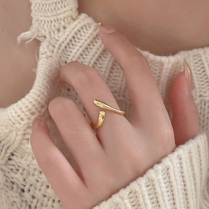 Close-up of a minimalist gold wavy open ring styled on a model in a knit sweater