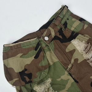 Détail du short camouflage avec boutons métalliques et texture de tissu usé et déchiré
