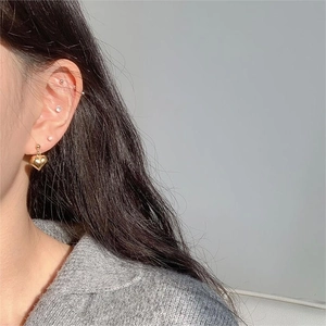 Detail of 925 silver heart earring and pearl stud set worn on the ear for women