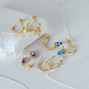 Detail of S925 sterling silver earrings with colorful teardrop stones on white rock