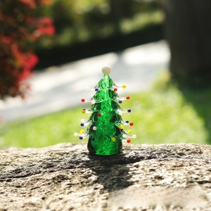 Close-up of a handmade green glass Christmas tree figurine with colorful ornaments