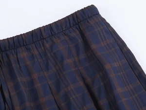 Macro view of elastic waistband on dark navy and brown plaid wide-leg trousers