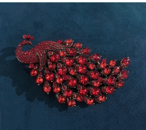 Detail of red crystal peacock brooch with ruby rhinestones and vintage gold setting