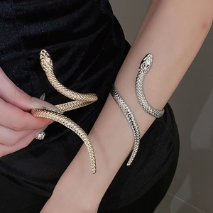 Detail showing gold and silver snake-shaped bracelets with realistic scale textures