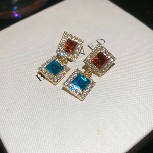 Détail de boucles d'oreilles vintage carrées avec cristaux bleus et bruns sur base dorée