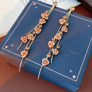 Close-up of pink rose fringe earrings with champagne crystals and gold metal chains
