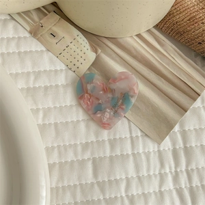 Detailed macro of pink and blue marble pattern heart-shaped hair clips on white fabric