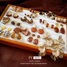 Close-up of vintage style earring collection in warm earth tones on a white display tray