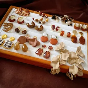 Close-up of vintage style earring collection in warm earth tones on a white display tray