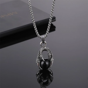 Vue macro détaillée d'un pendentif griffe de dragon tenant une sphère d'obsidienne noire lisse