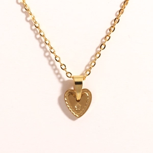 Detailed macro shot of a gold heart pendant with wavy edges and star motif on a chain