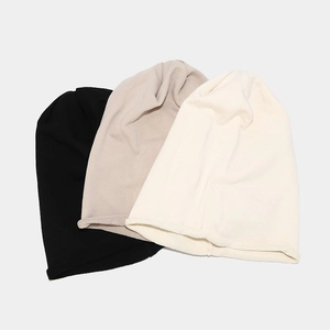 Close-up of knit beanies in black, light grey, and cream with soft rolled edges