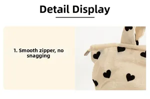 Detail of smooth silver zipper on a beige plush heart pattern canvas shoulder bag