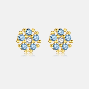 Detail view of flower studs with blue gemstones and gold finish on s925 silver needles