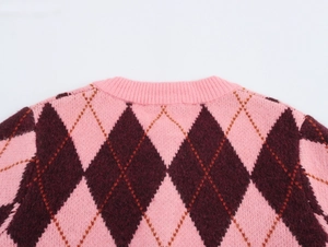 Close-up of pink and brown argyle knit sweater showing ribbed crew neck and plush texture