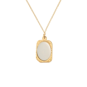 Detailweergave van de gouden vierkante hanger ketting met wit inlegwerk en een reliëf frame