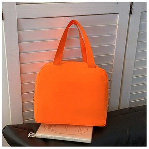 Close-up of orange insulated lunch bag featuring waterproof fabric and top handle design