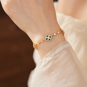Gros plan d'un bracelet fleuri doré avec des pierres vertes et des zircons scintillants
