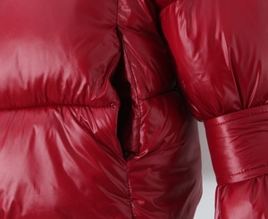 Detail of glossy red puffer jacket showing side pocket and smooth stitching on shiny fabric