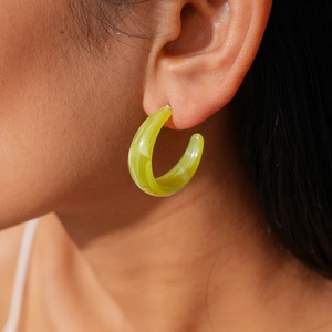 Close-up of green marble acrylic C-shaped hoop earring worn for fashion look