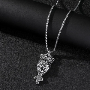 Gros plan d'un pendentif croix lion couronné en argent avec acier inoxydable poli