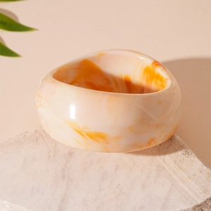 Detail of irregular resin bangle with marble texture on a natural stone display stand