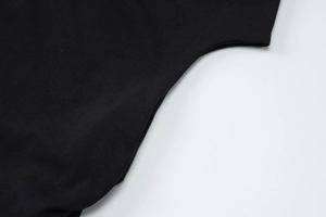 Gros plan détaillé sur la texture en maille de coton noir et les coutures du T-shirt