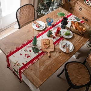 Christmas table runner with snowman patterns, reindeer prints and red tassels on wooden table