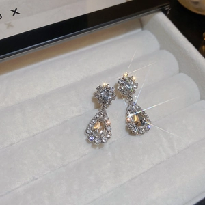 Macro shot of silver teardrop crystal earrings in a white velvet jewelry box with star flare