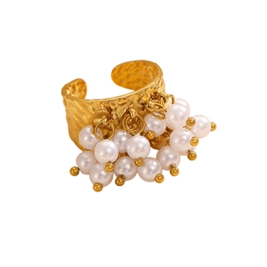 Detail of bohemian gold ring with hammered texture and dangling white pearl tassels