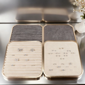 Square gold metal jewelry tray with beige and grey velvet inserts for rings and earrings