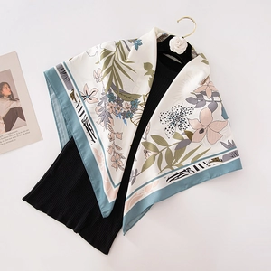 Off-white silk scarf with floral botanical print on black knit top with a gold hanger