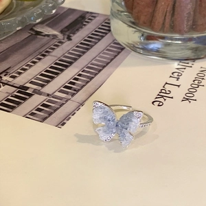 Detailed view of an adjustable gold-plated butterfly ring with blue stones and pearls