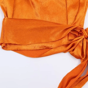 Fashionable orange satin blouse for women featuring an elegant bow tie and pleated detail