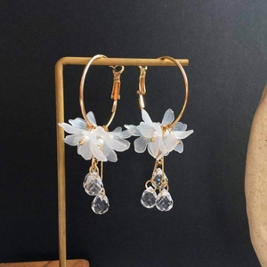 Elegant gold hoop earrings with white acrylic flowers and hanging crystal droplets