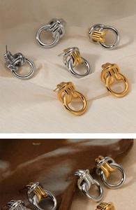 Detail of twisted knot hoop earrings in polished gold and silver two-tone metallic finish