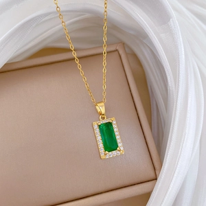Macro view of gold-plated square necklace with green center stone and white diamonds