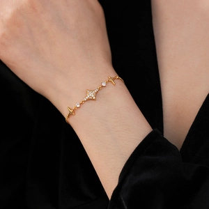 Close-up of gold starburst bracelet with cubic zirconia on wrist with black background