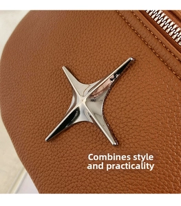 Detailed macro shot of a brown pebbled leather bag with silver star logo and metal zipper