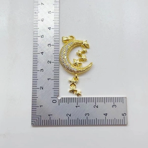 Gold star and moon pendant with white zircon inlays and scale for size reference