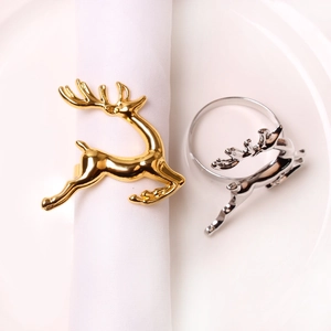 Close-up of gold and silver reindeer metal napkin rings on a white ceramic plate
