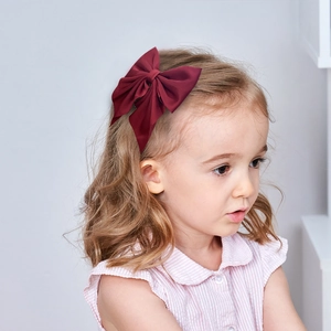 Elegant deep red oversized fabric bow hair clip shown on a girl for academic style