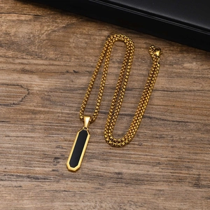 Macro detail of geometric long bar pendant with black inlay on a golden chain