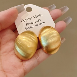 Detailed macro view of vintage brushed gold metallic geometric earrings on display card