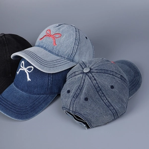 Detailaufnahme der Textur des Jeansstoffs und der gestickten Schleife auf den Baseballkappen