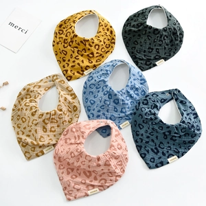 Flat lay of multiple leopard print cotton baby bibs in assorted colors on white background