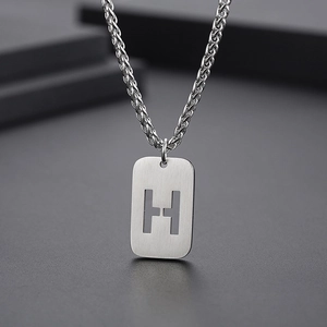 Vue macro du pendentif lettre H en argent avec texture en métal brossé sur chaîne