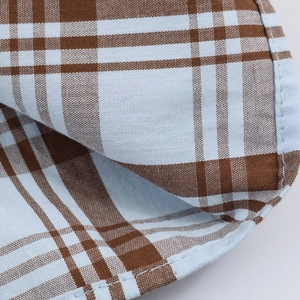 Detail of classic brown and light blue plaid pattern cotton fabric with neat stitching